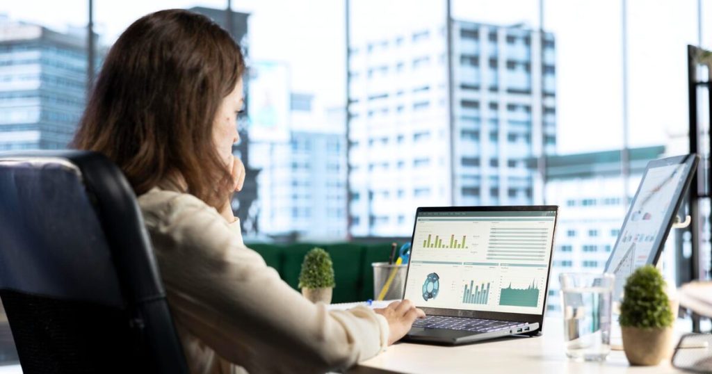 Analyst monitoring a web traffic dashboard on a laptop overlooking a city